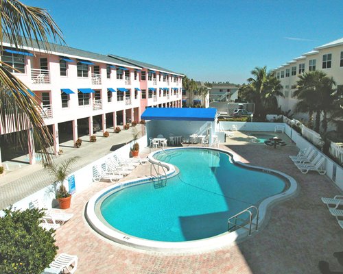 An outdoor swimming pool with chaise lounge chairs alongside the multi story resort unit.