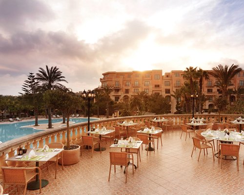 An outdoor fine dining restaurant alongside multi story units and swimming pool.