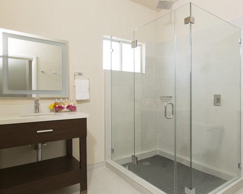 A bathroom with a stand up shower and single sink vanity.