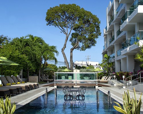 An outdoor swimming pool with chaise lounge chairs and sunshades.