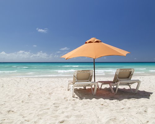 A view of chaise lounge chairs with sunshades in the beach.