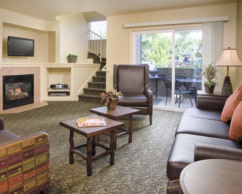 A well furnished living room with a television fire in the fireplace and patio.