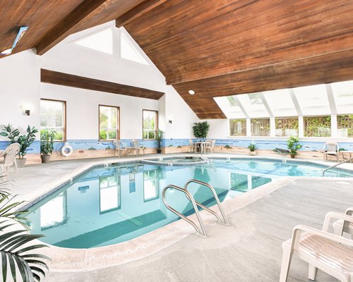 An indoor swimming pool with patio furniture.