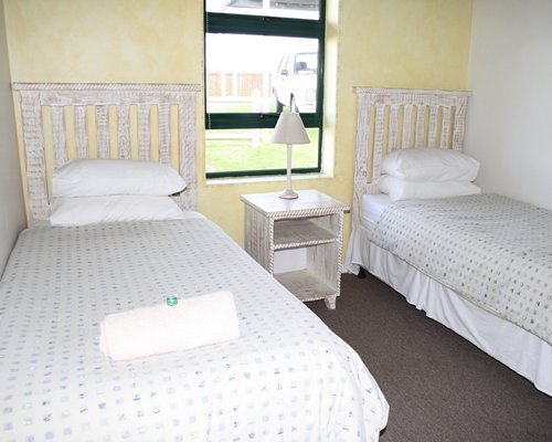 A well furnished bedroom with two twin beds and outside view.