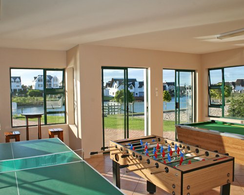 A recreational room with pool table ping pong foosball table and patio.