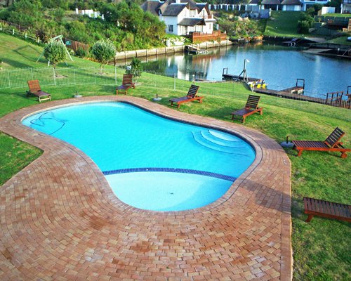 Scenic outdoor swimming pool with chaise lounge chairs alongside the resort with the waterfront.
