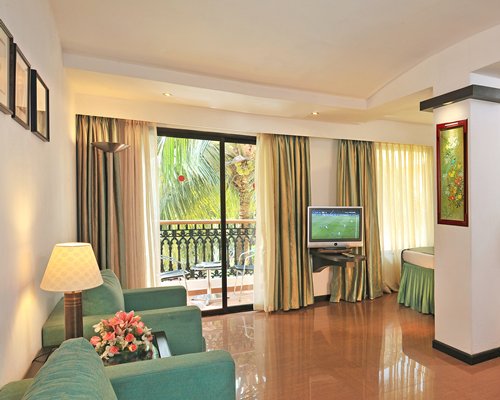 An open plan bedroom and living area with a television alongside a balcony with patio.