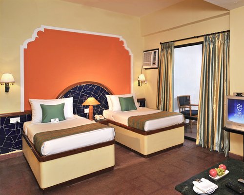 A well furnished bedroom with two beds and television.