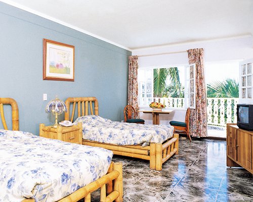 A well furnished bedroom with twin beds a television and balcony.