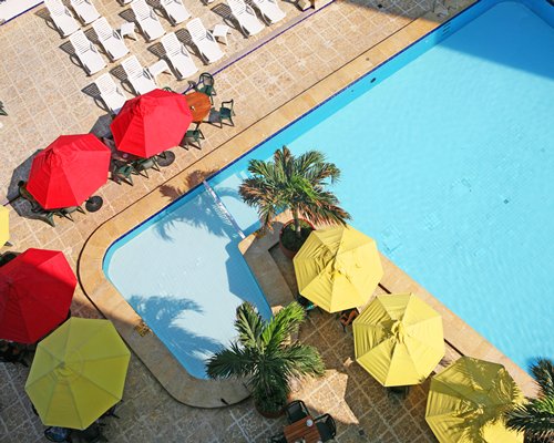 An outdoor swimming pool with chaise lounge chairs and sunshades.