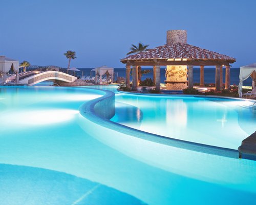 An outdoor swimming pool with poolside bar at night.