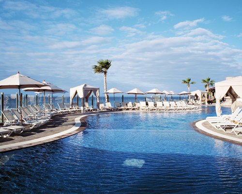An outdoor swimming pool with chaise lounge chairs and sunshades.