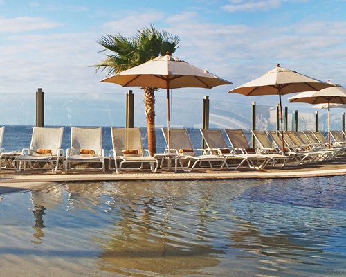 A large outdoor swimming pool with chaise lounge chairs and sunshades.