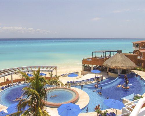 A large outdoor swimming pool with a hot tub and chaise lounge chairs alongside the beach.