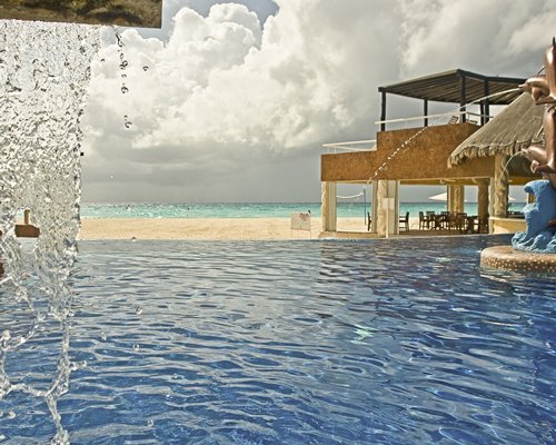 An outdoor swimming pool with water feature facing the sea.