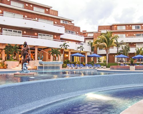 An outdoor swimming pool with chaise lounge chairs and umbrellas alongside the resort.