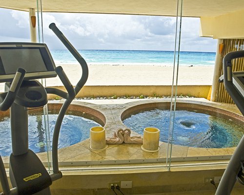 A well equipped indoor fitness center alongside two hot tubs.