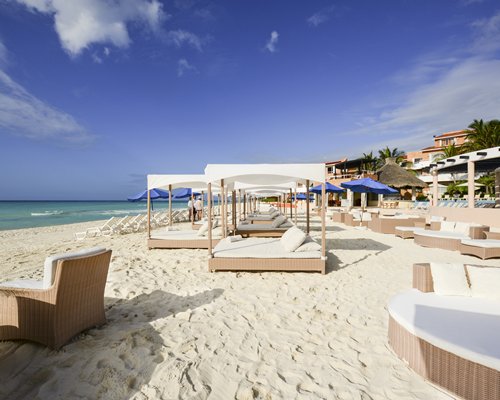 A view of the beach beds with chaise lounge chairs and sunshades alongside the sea.