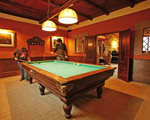 People playing pool table at an indoor recreation room.