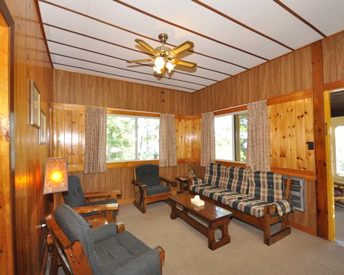 A well furnished wood themed living room with sofas and an outside view.
