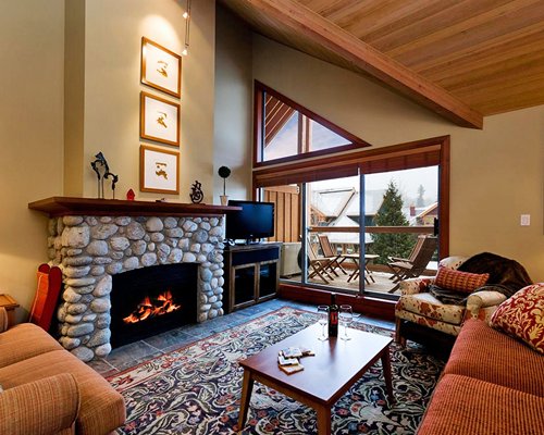 A well furnished living room with television fire in the fireplace and a balcony.