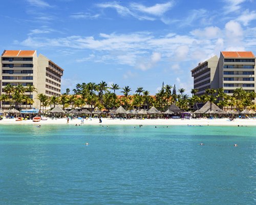 Exterior view of Barcelo Aruba resort with trees alongside the sea.