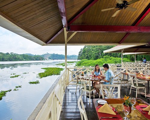 A well furnished fine dining restaurant surrounded by trees with a waterfront view.