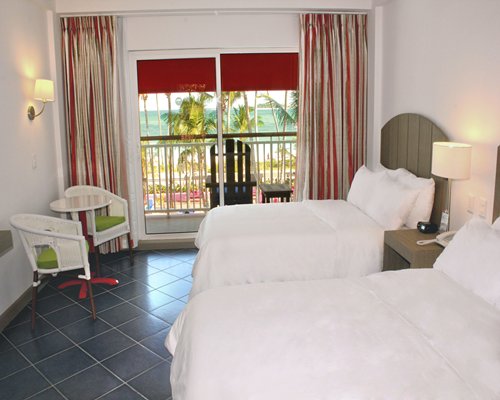 A well furnished bedroom with two beds alongside the balcony.