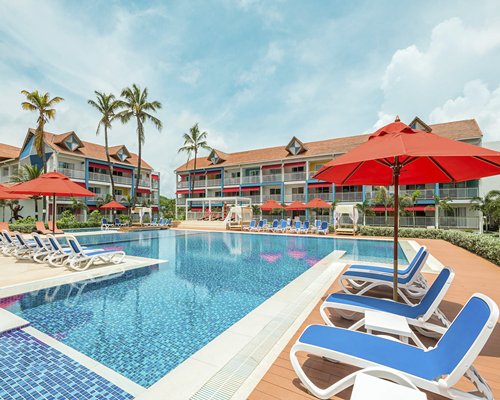 An outdoor swimming pool with chaise lounge chairs and umbrellas alongside the resort.