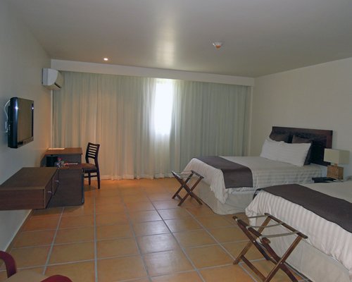 A well furnished bedroom with two beds and a television.