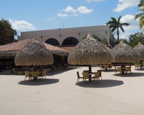 A patio furniture with thatched sunshades alongside the resort unit.