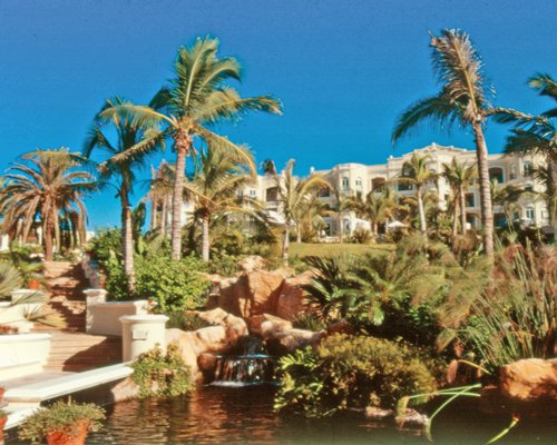 Scenic exterior view of Pueblo Bonito Resort alongside the waterfront with grotto waterfall and a pathway.