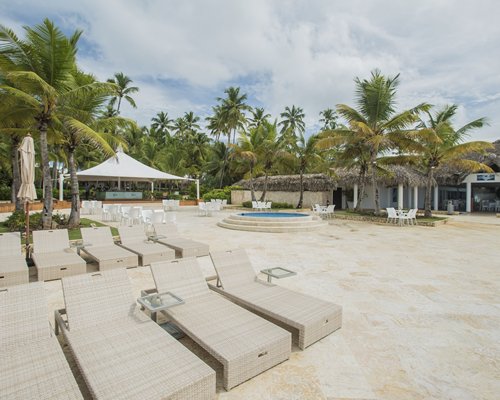 Outdoor hot tub and picnic area with chaise lounge chairs patio furniture and palm trees.