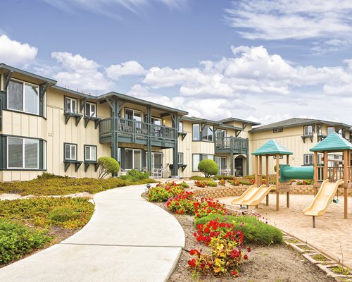 Scenic exterior view of the WorldMark Monterey Bay resort alongside a pathway and playscape area.