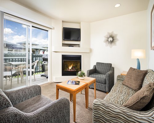 A well furnished living room with a television fire in the fireplace and balcony.