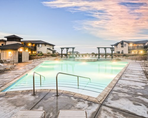 An outdoor swimming pool with chaise lounge chairs alongside multiple resort units.