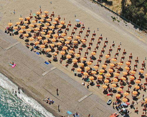 An aerial view of the beach with sunshades alongside the sea.