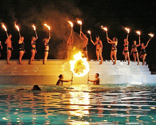 People entertaining with fire at an outdoor swimming pool.