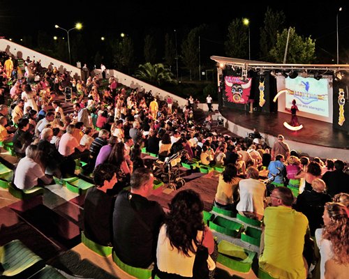 People watching the entertainment show at outdoor venue with a stage.