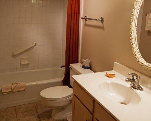 A bathroom with a bathtub shower and single sink vanity.