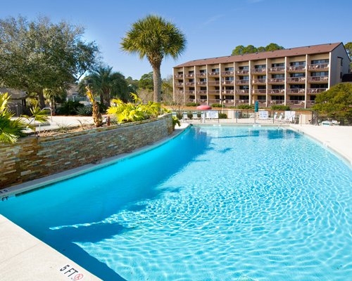 An outdoor swimming pool with trees alongside multi story resort units.