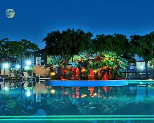 An outdoor swimming pool with chaise lounge chairs at night.
