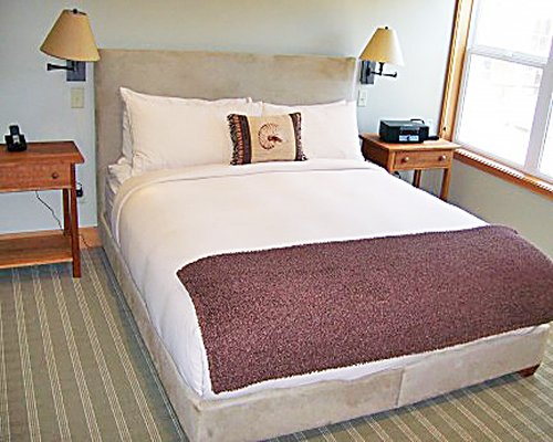 A well furnished bedroom with two lamps and an outside view.