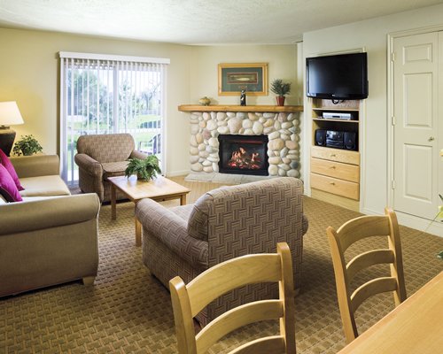 A well furnished living room with a sofa television and fire in the fireplace.