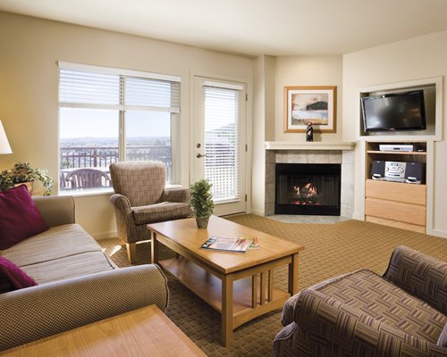 A well furnished living room with a television fire in the fireplace and balcony.