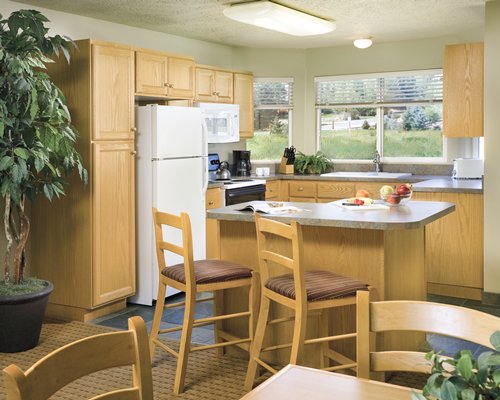 An open plan kitchen with breakfast bar dining area and outside view.