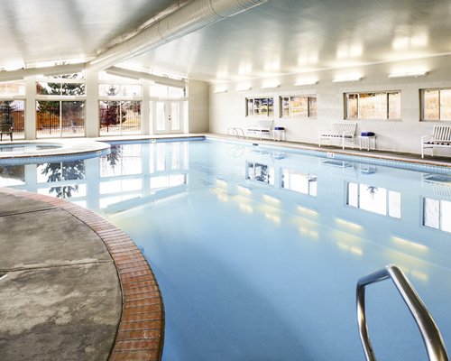 An indoor swimming pool and hot tub with an outside view.