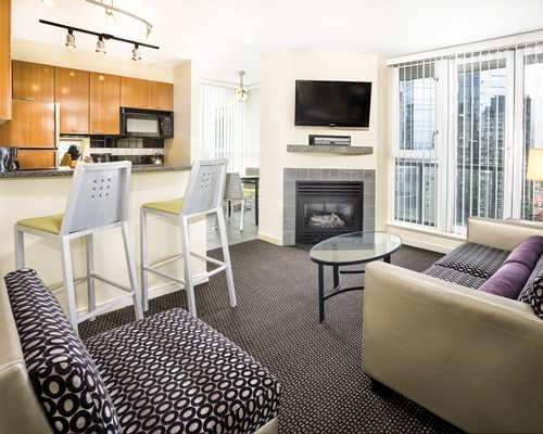 A well furnished living room with a television alongside a kitchen.