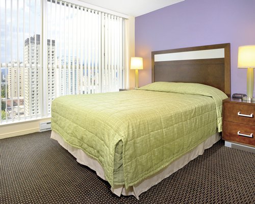 A well furnished bedroom with a queen bed and an outside view.