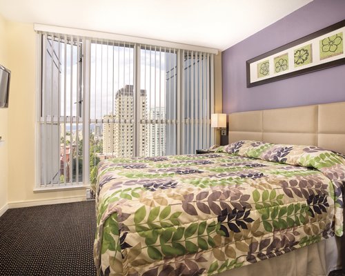 A well furnished bedroom with queen bed and outside view.